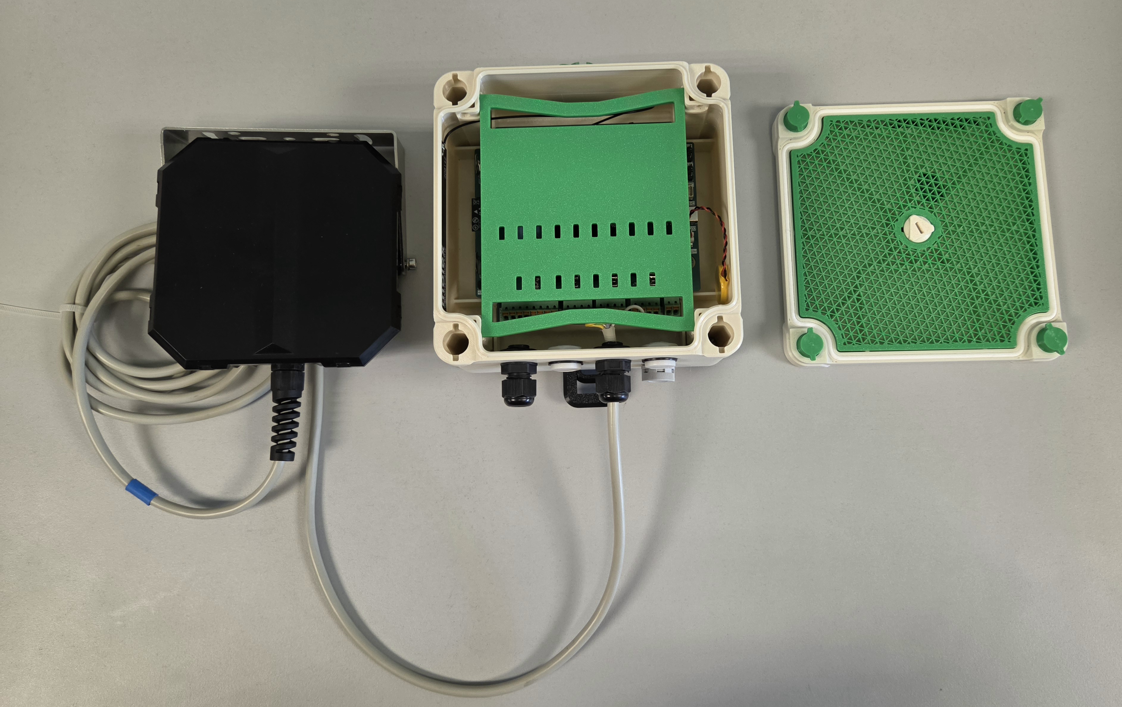 The test setup on the bench: the Paratronic NRV485 radar sensor, the ISURLOG open in its 3D-printed PETG enclosure, and the enclosure lid to the side